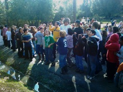 Large group of students outside at shady creek. 